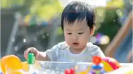 Toddler enjoying outdoor early learning activity in sensory water table
