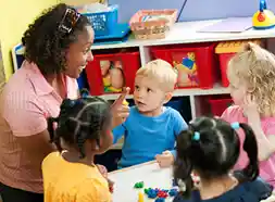 Preschool teacher at table with children